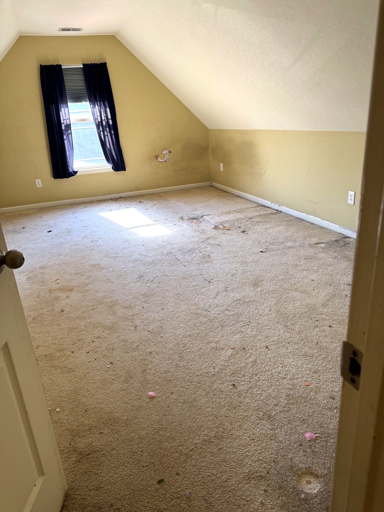 Upstairs bedroom before renovation with worn carpet and yellow walls